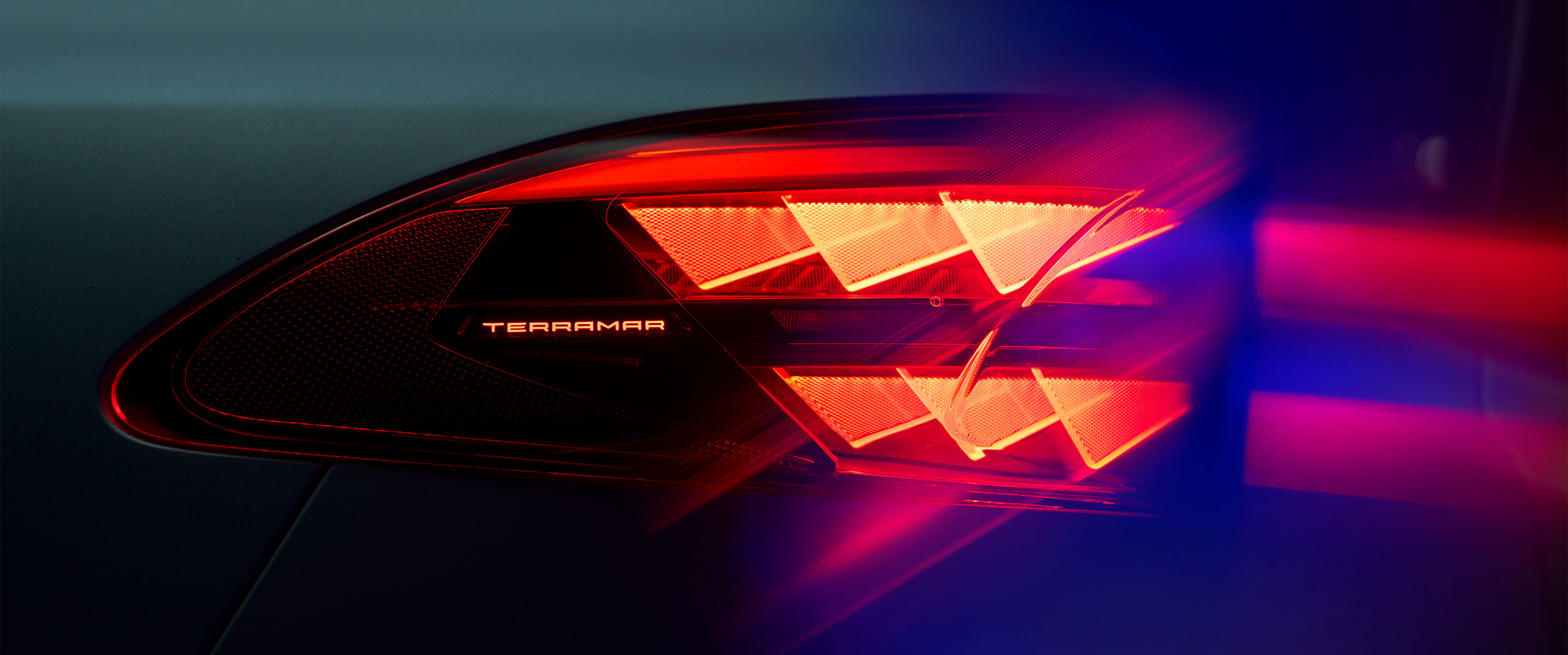 cupra terramar gros plan du feu arrière avec le nom du modèle éclairé, montrant le motif lumineux triangulaire rouge distinctif sur fond sombre