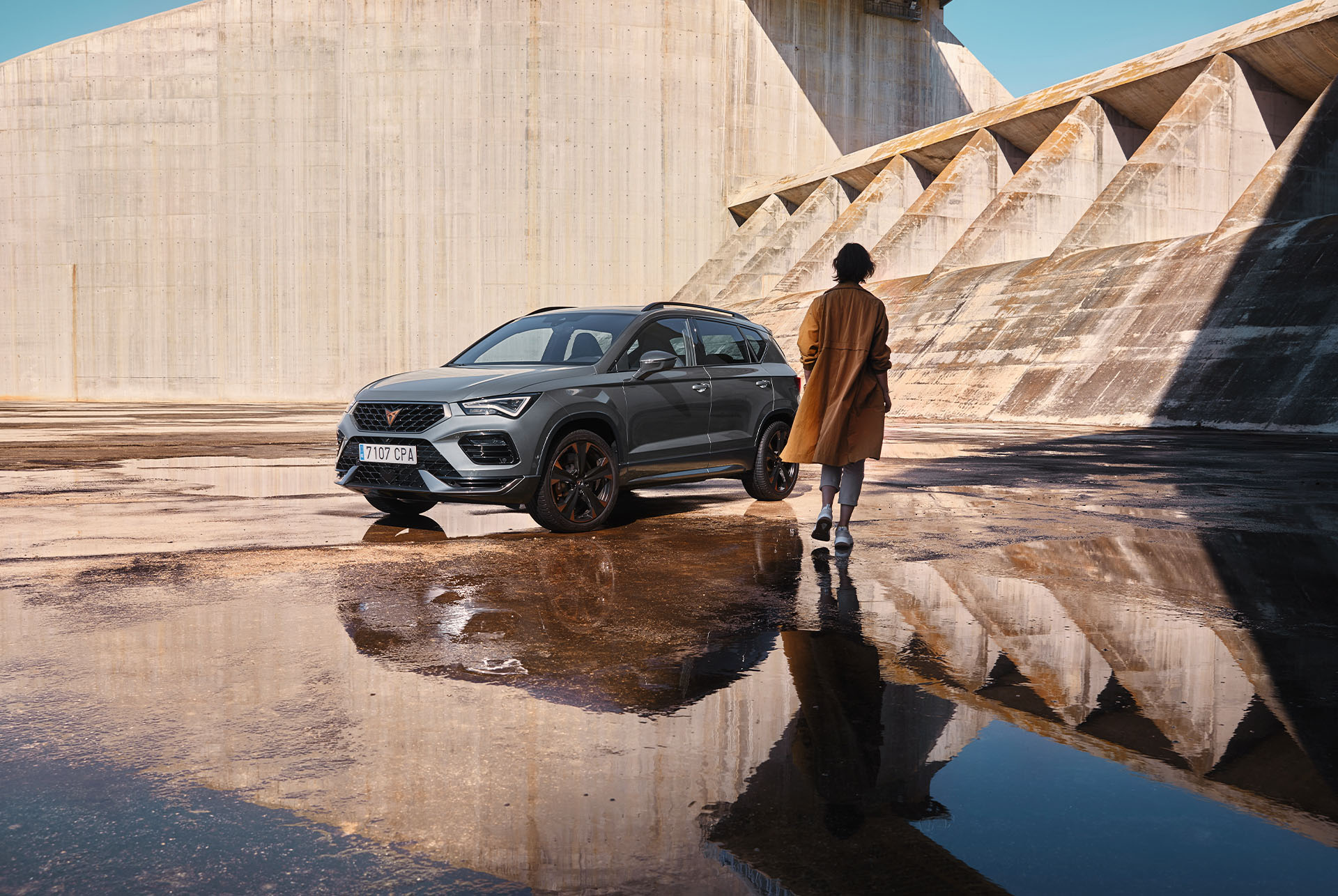 L’image montre une personne marchant vers une CUPRA Ateca et met en valeur les lignes audacieuses et athlétiques de la voiture et sa forme dynamique, représentant l’esprit de la tribu CUPRA. 