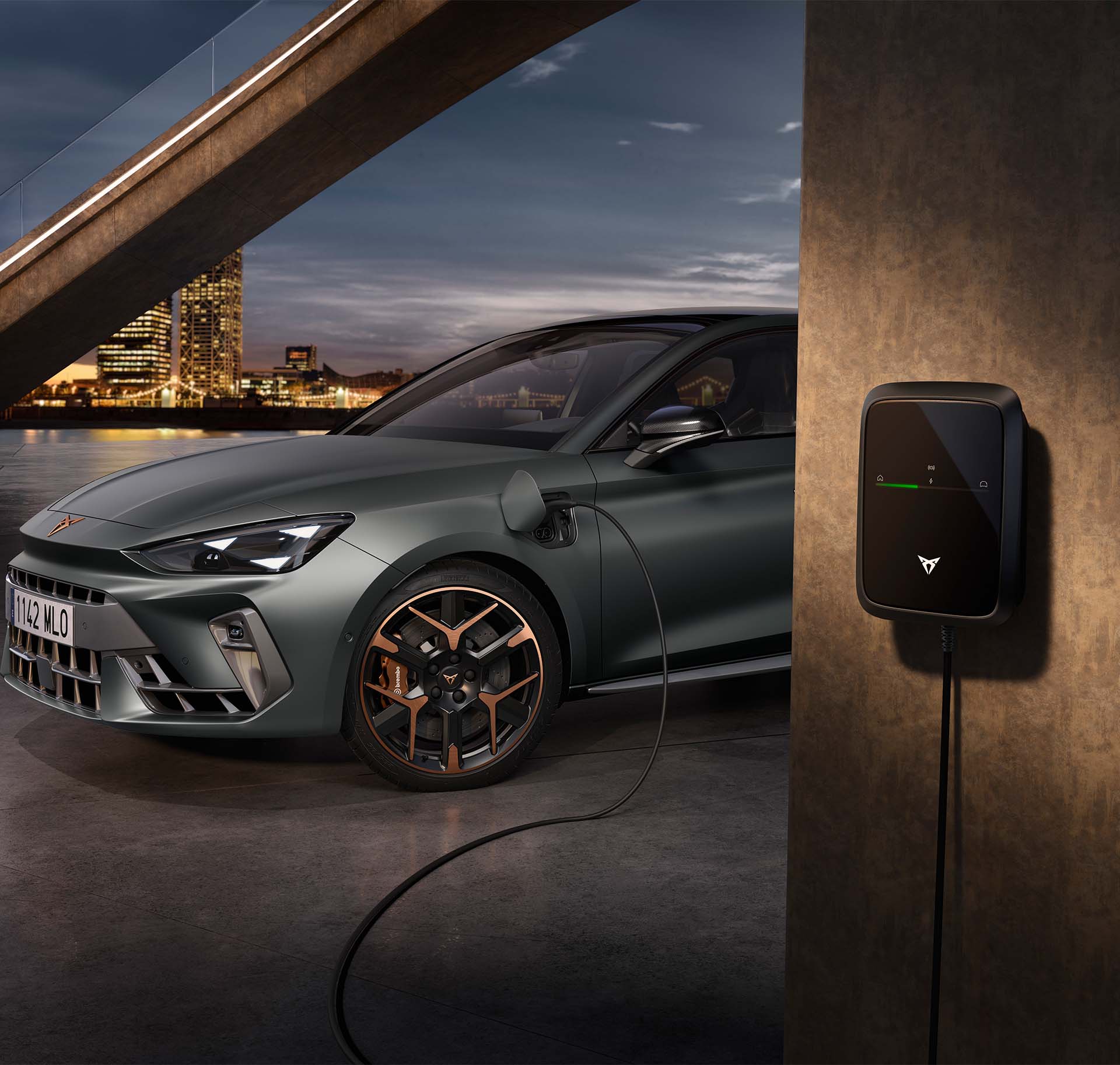 front left side view of the new century bronze matt cupra formentor 2024 with copper accent wheels, on charge, Barcelona cityscape background view at dusk